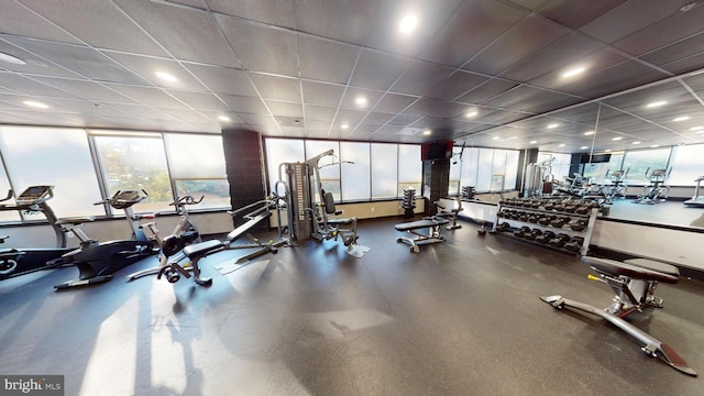 exercise room with a paneled ceiling and a wall of windows