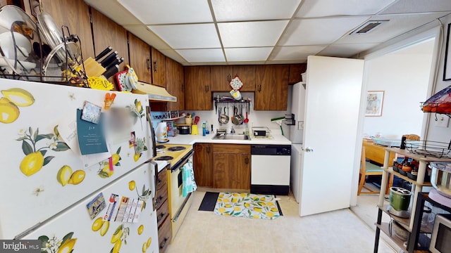 kitchen featuring a drop ceiling, white appliances, and sink