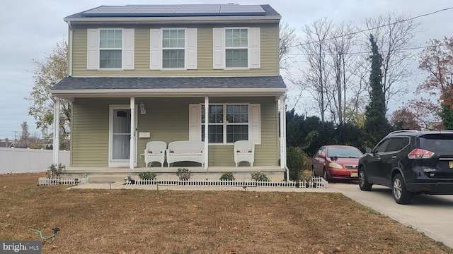 front of property with solar panels, covered porch, and a front yard