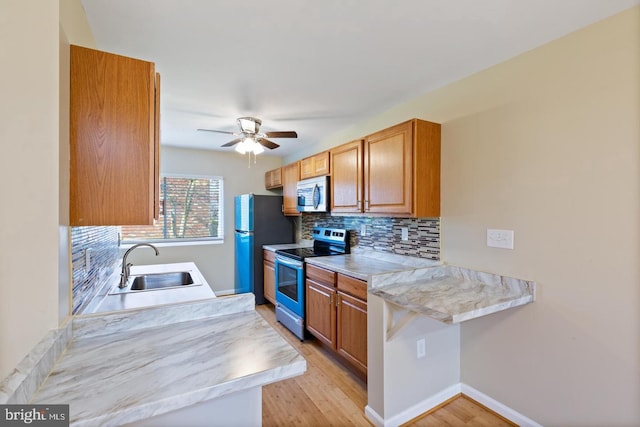 kitchen featuring tasteful backsplash, stainless steel appliances, ceiling fan, sink, and light hardwood / wood-style flooring