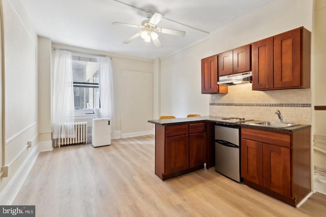 kitchen featuring radiator heating unit, kitchen peninsula, decorative backsplash, and light hardwood / wood-style floors