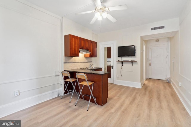 kitchen with decorative backsplash, light hardwood / wood-style floors, kitchen peninsula, and ceiling fan