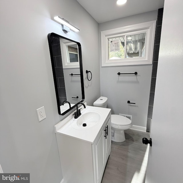 bathroom with toilet, wood-type flooring, and vanity