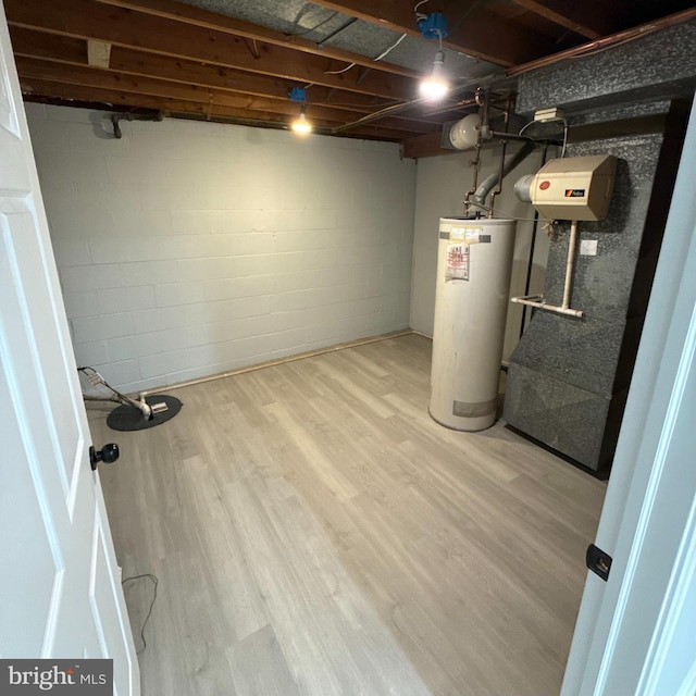 basement featuring water heater and hardwood / wood-style flooring