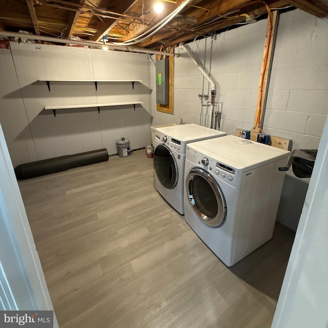 washroom featuring electric panel, separate washer and dryer, and light hardwood / wood-style flooring