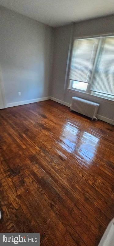 unfurnished room featuring radiator and dark hardwood / wood-style flooring