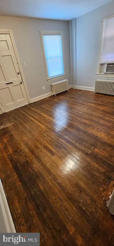 empty room with dark hardwood / wood-style floors and radiator