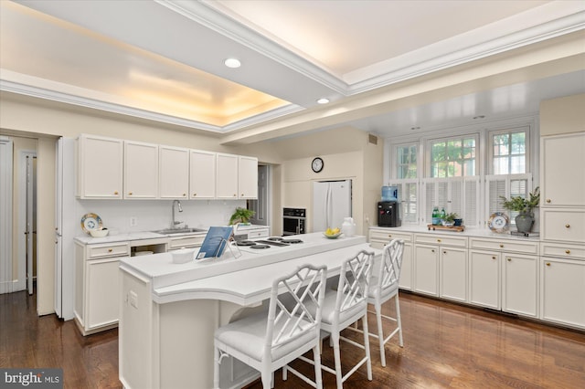 kitchen featuring white cabinetry, a breakfast bar, a kitchen island, and white fridge