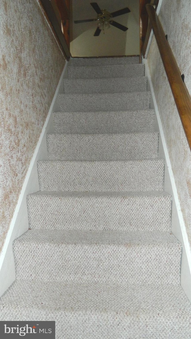 stairway featuring ceiling fan