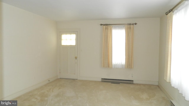 empty room with a baseboard heating unit and light carpet