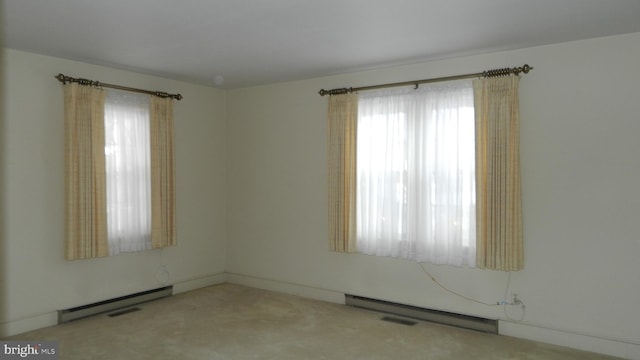 carpeted spare room featuring a wealth of natural light and a baseboard heating unit