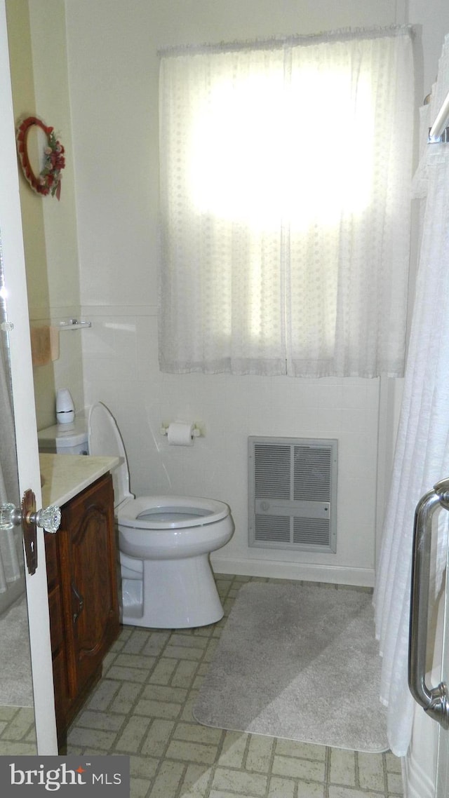 bathroom featuring vanity, toilet, and heating unit