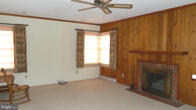 carpeted living room with a baseboard heating unit, wooden walls, ceiling fan, ornamental molding, and a brick fireplace