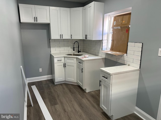 kitchen with dark hardwood / wood-style flooring, decorative backsplash, sink, and white cabinets