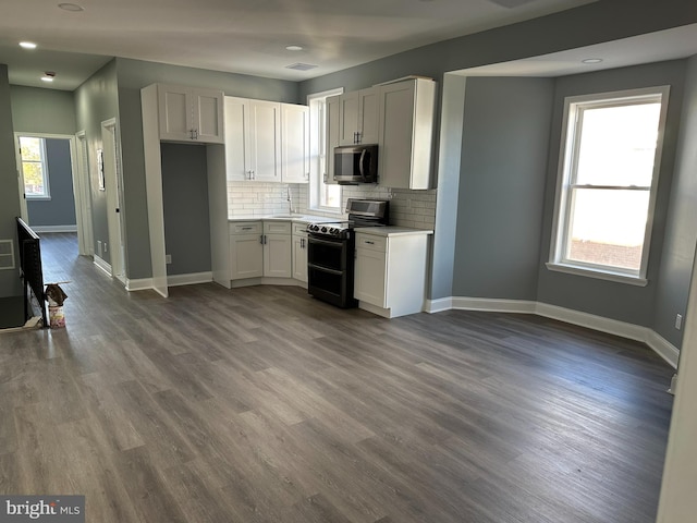 kitchen with white cabinets, dark wood-type flooring, black range oven, and a healthy amount of sunlight