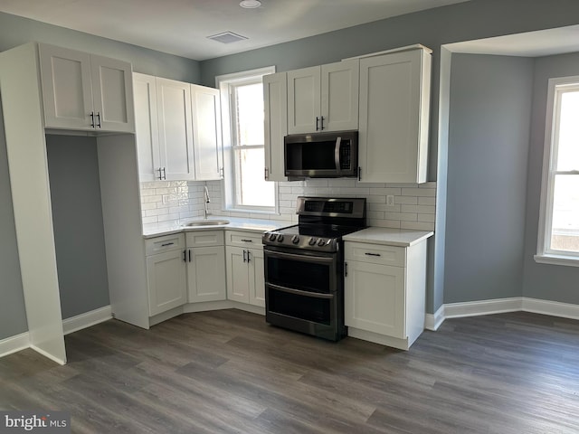 kitchen featuring decorative backsplash, appliances with stainless steel finishes, dark wood-type flooring, sink, and white cabinetry