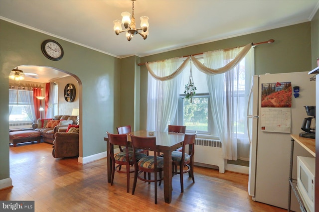 dining space featuring crown molding, hardwood / wood-style floors, ceiling fan with notable chandelier, and radiator heating unit