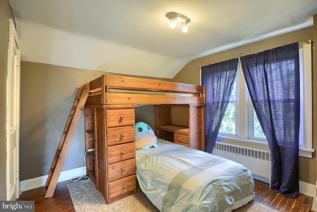 bedroom with radiator, wood-type flooring, and vaulted ceiling