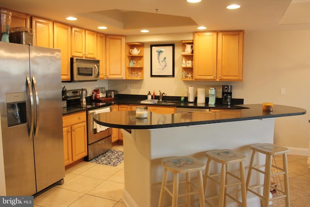 kitchen with kitchen peninsula, appliances with stainless steel finishes, a kitchen bar, and light tile patterned floors