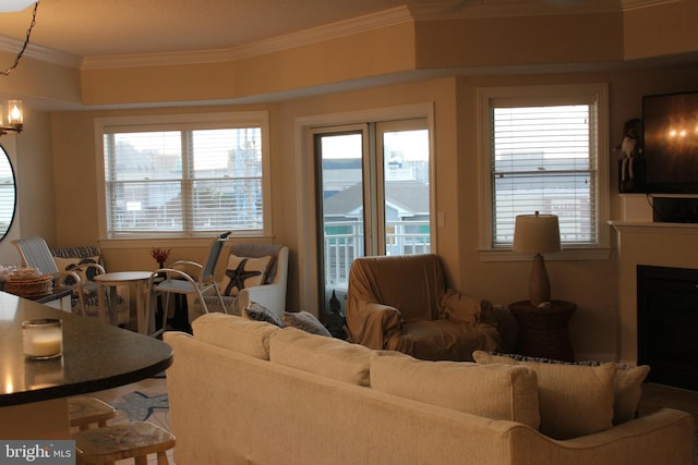 living room featuring plenty of natural light, crown molding, and an inviting chandelier