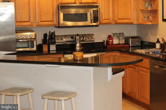 kitchen with light tile patterned floors, stainless steel appliances, and a breakfast bar area