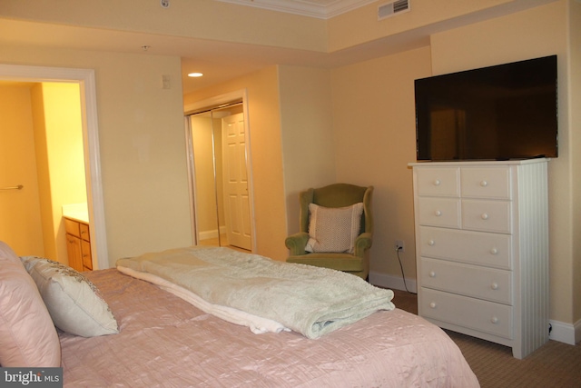 carpeted bedroom featuring ornamental molding, connected bathroom, and a closet