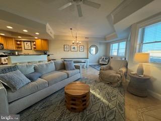 living room with ceiling fan with notable chandelier and crown molding