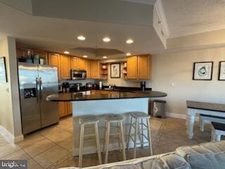 kitchen featuring appliances with stainless steel finishes, a kitchen breakfast bar, and light tile patterned flooring