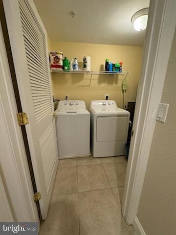 clothes washing area featuring washer and clothes dryer and light tile patterned floors