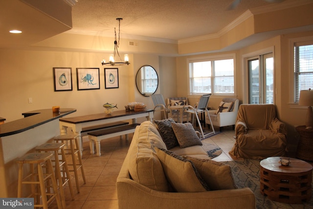 living room with light tile patterned floors, plenty of natural light, ornamental molding, and a notable chandelier