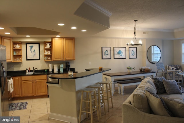 kitchen featuring sink, a kitchen breakfast bar, a chandelier, decorative light fixtures, and light tile patterned flooring