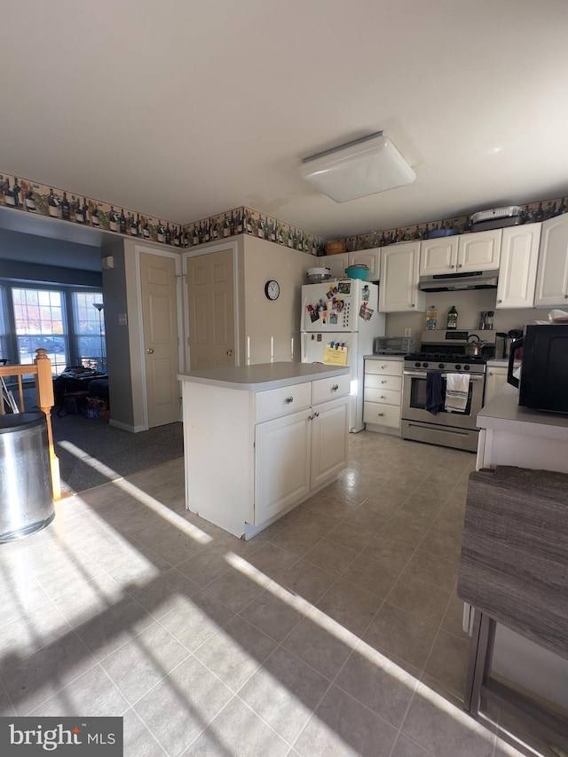 kitchen featuring white cabinets, white refrigerator, light tile patterned floors, and stainless steel gas range