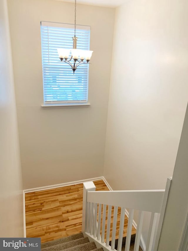 stairs featuring hardwood / wood-style floors and a chandelier