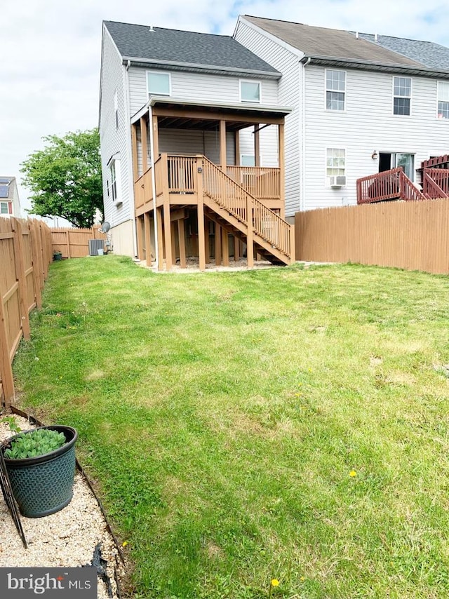 rear view of house with a yard, a deck, and cooling unit