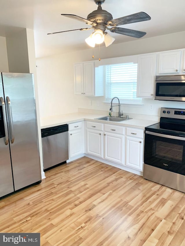 kitchen with sink, white cabinets, stainless steel appliances, and light hardwood / wood-style floors