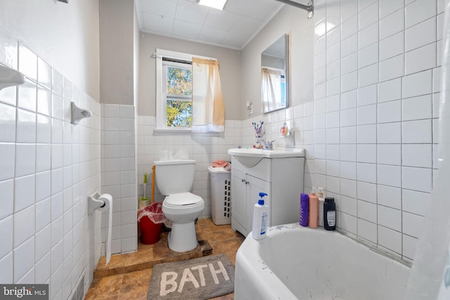 bathroom with a tub, vanity, tile walls, and toilet