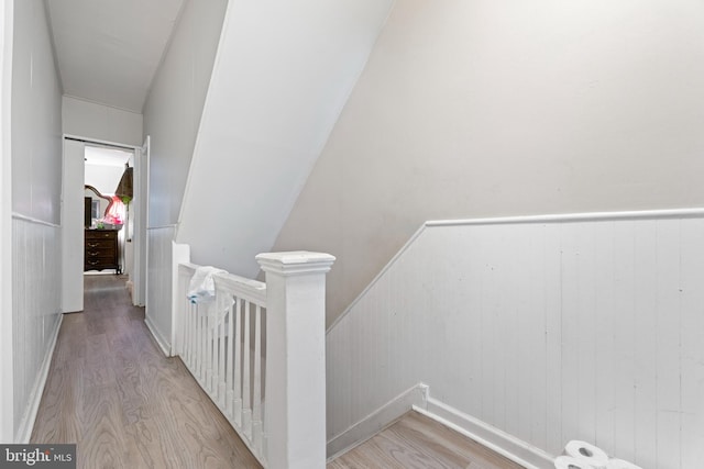 stairway with wood walls, lofted ceiling, and hardwood / wood-style flooring