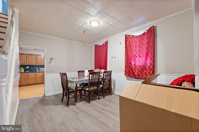 dining room with light hardwood / wood-style flooring and crown molding