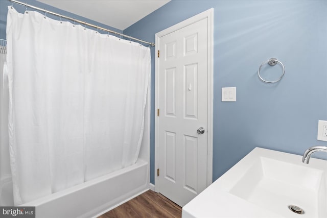 bathroom with wood-type flooring, shower / bath combination with curtain, and sink