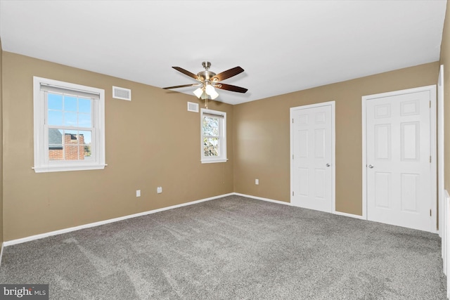 unfurnished bedroom with ceiling fan, carpet floors, and two closets