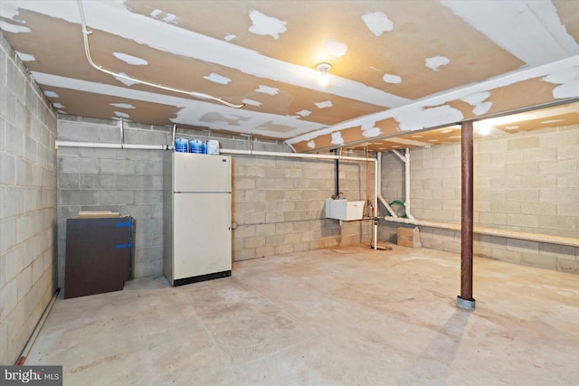 basement featuring sink and white fridge