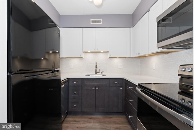 kitchen featuring backsplash, stainless steel appliances, dark wood-type flooring, sink, and white cabinets