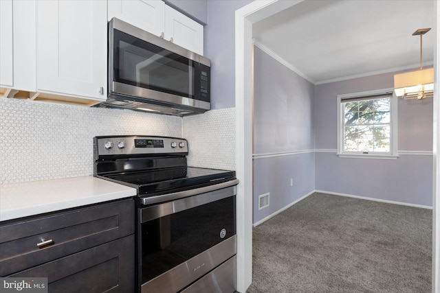 kitchen featuring decorative backsplash, stainless steel appliances, crown molding, pendant lighting, and white cabinetry