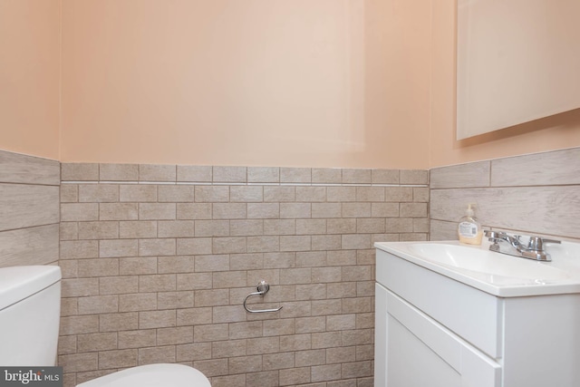 bathroom featuring vanity, tile walls, and toilet