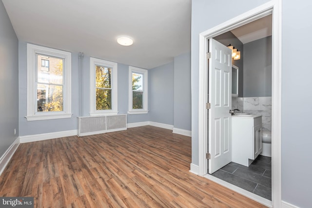 spare room with dark hardwood / wood-style floors, sink, and radiator