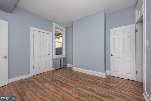 unfurnished bedroom featuring dark hardwood / wood-style floors and radiator