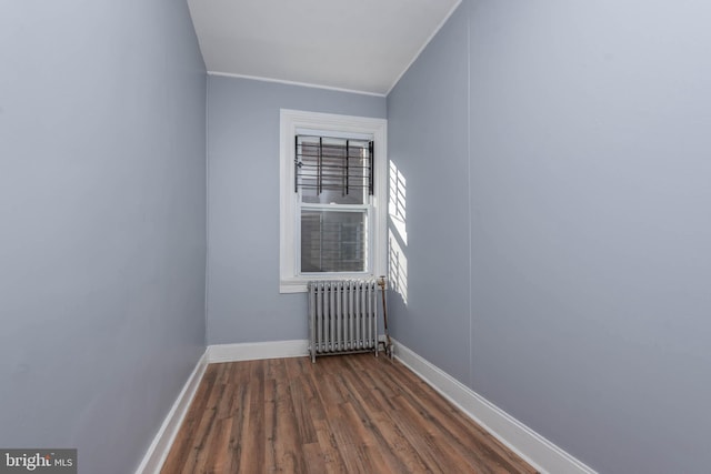 empty room featuring crown molding, dark wood-type flooring, and radiator