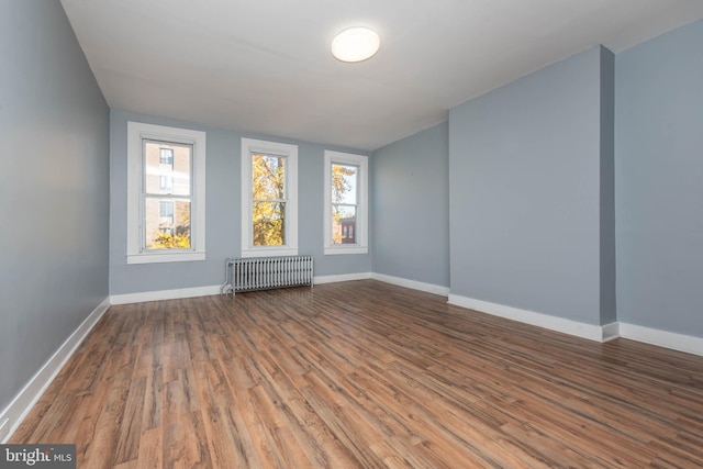 spare room featuring wood-type flooring and radiator