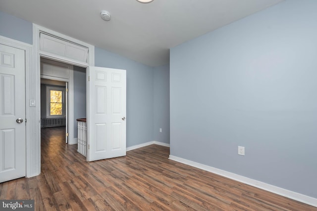 unfurnished room featuring vaulted ceiling, radiator, and dark wood-type flooring