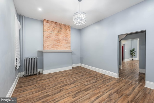 empty room featuring radiator heating unit, dark wood-type flooring, and a notable chandelier